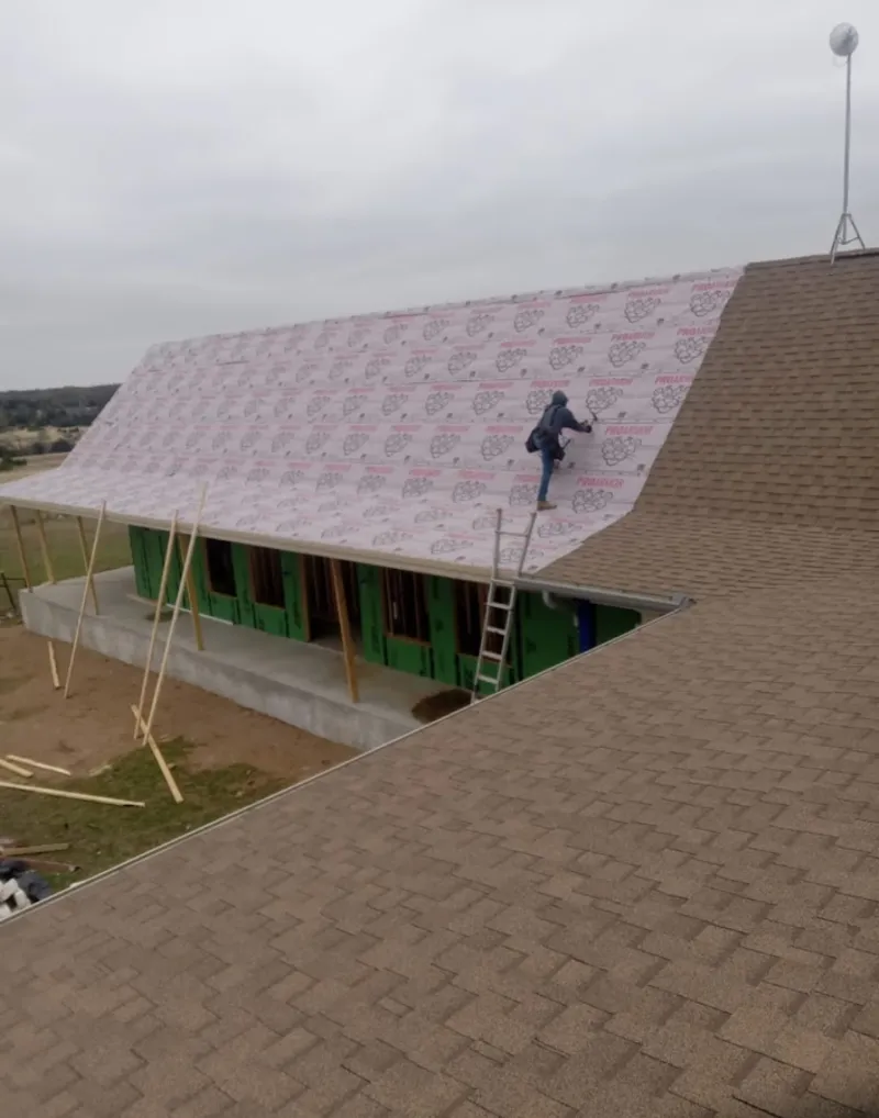 Worker preparing underlayment for a metal roof installation in Destin